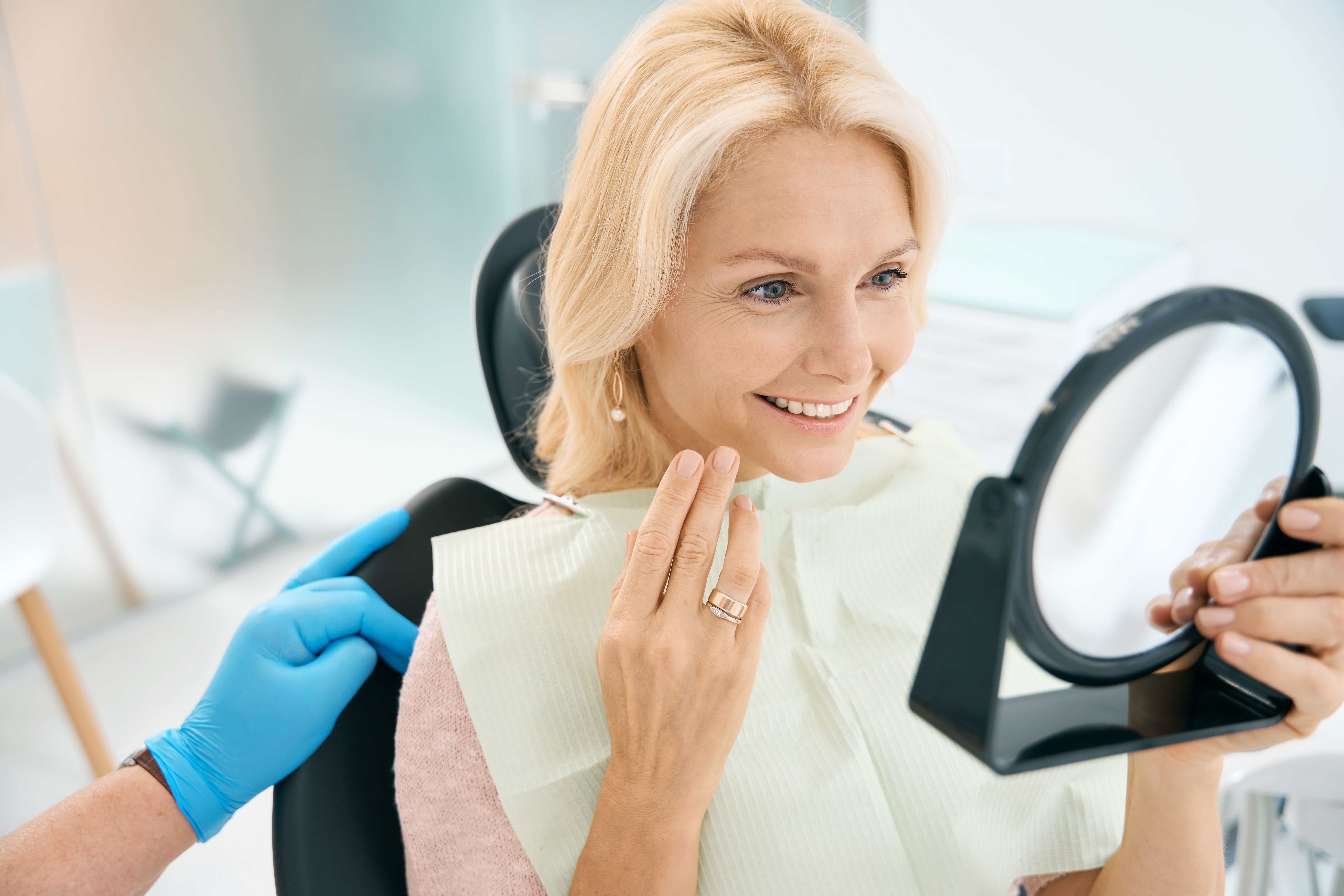 Patient looking at her smile in a mirror after dental care